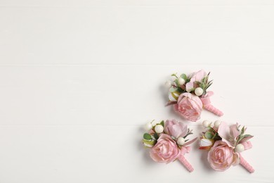 Photo of Beautiful boutonnieres on white background, flat lay. Space for text