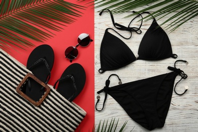 Flat lay composition with black swimsuit and beach accessories on color background