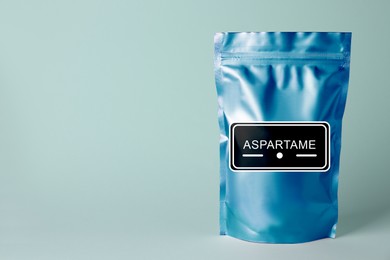 Image of Aspartame. Blue foil package with artificial sweetener on light background, space for text