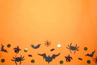 Photo of Flat lay composition with paper bats and spiders on orange background, space for text. Halloween decor