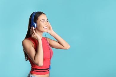 Photo of Attractive young woman enjoying music in headphones on color background. Space for text