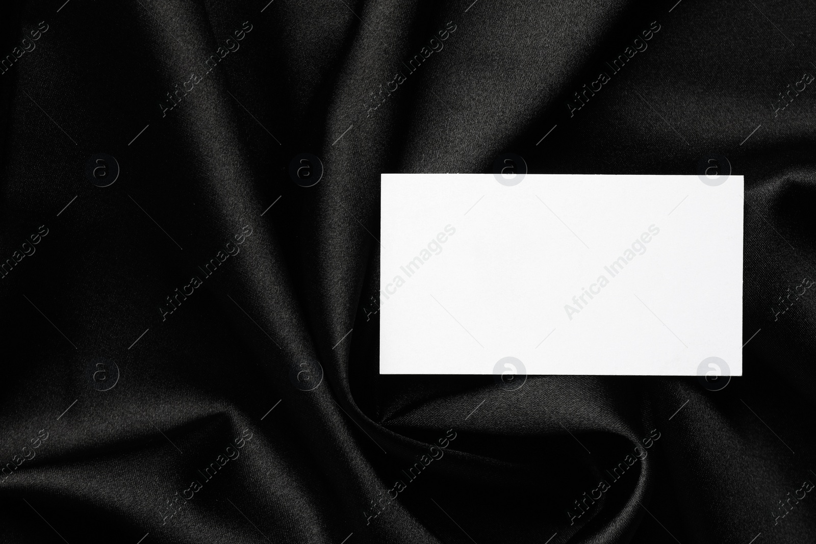 Photo of Blank business card on black fabric, top view. Mockup for design