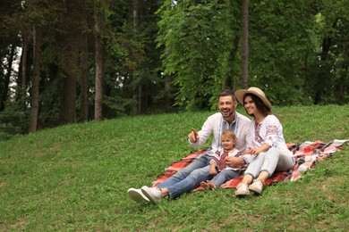 Photo of Happy family in Ukrainian national clothes on green grass outdoors