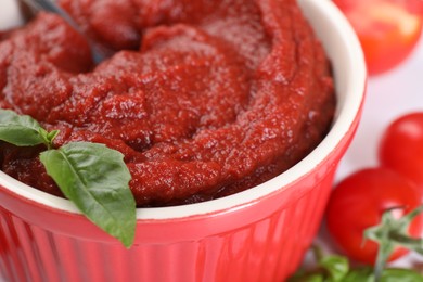 Photo of Tasty tomato paste and basil in bowl, closeup