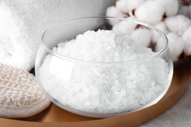 White sea salt for spa scrubbing procedure in glass bowl on grey table