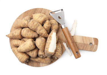 Photo of Tubers of turnip rooted chervil and peeler isolated on white, top view