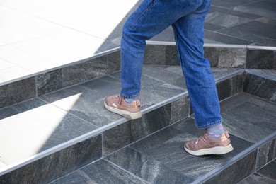 Photo of Woman walking up stylish stone stairs outdoors, closeup