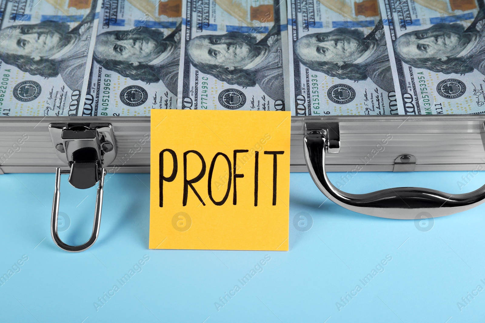 Photo of Economic profit. Note and briefcase with banknotes on light blue background, closeup