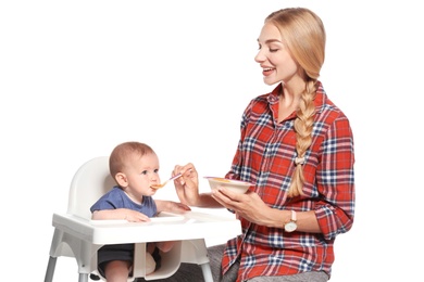 Woman feeding her child in highchair against white background. Healthy baby food