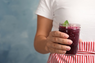 Photo of Woman holding mason jar of delicious acai juice, closeup