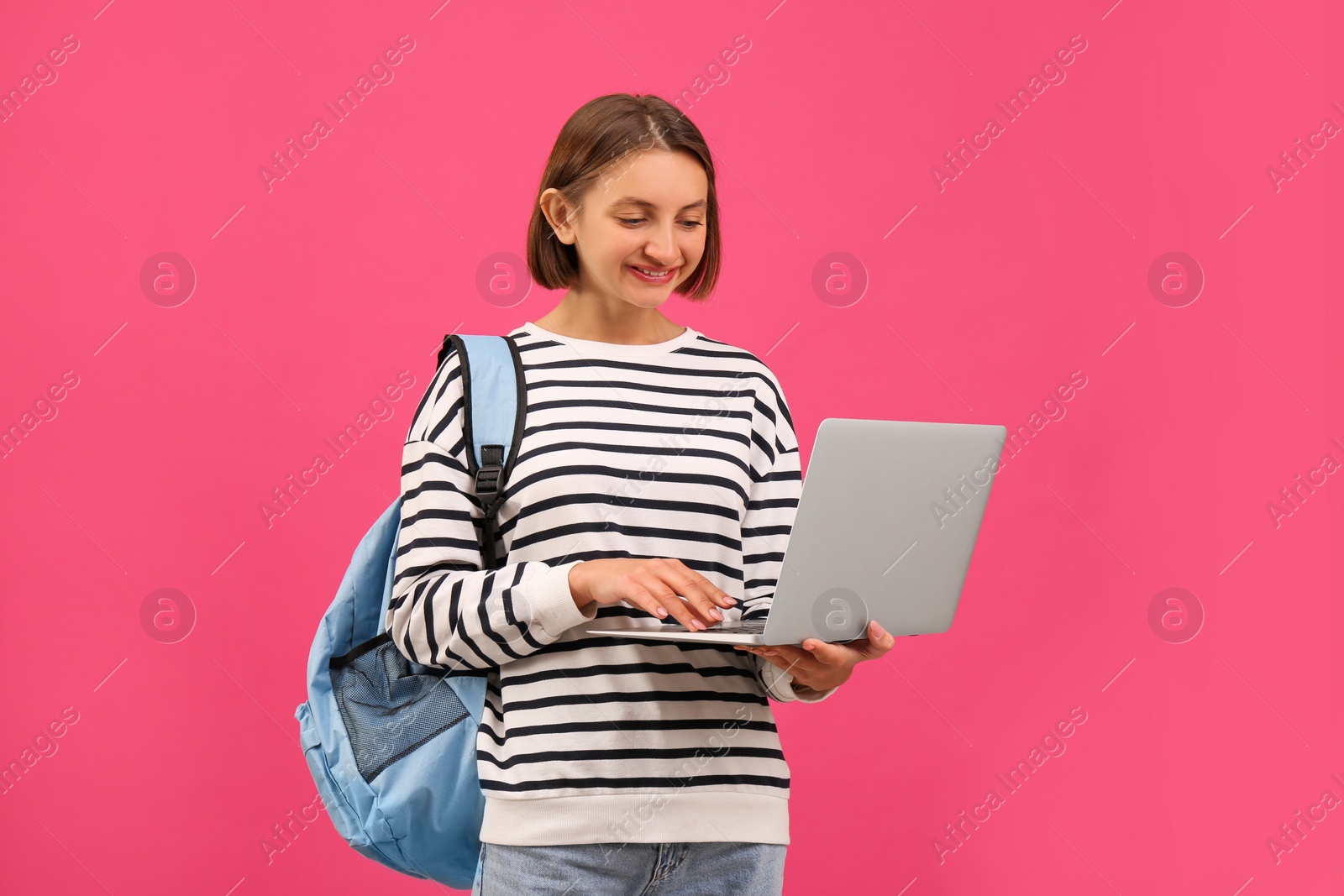 Photo of Young student with laptop and backpack on pink background