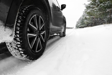 Photo of Snowy country road with car on winter day, closeup. Space for text