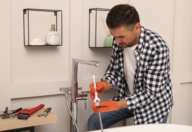 Photo of Man installing new water tap in bathroom