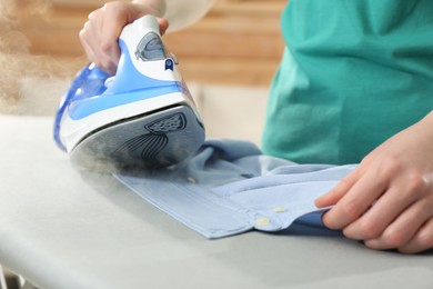 Photo of Woman ironing clean shirt at home, closeup