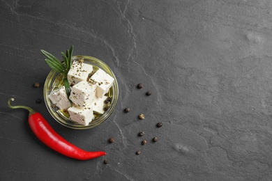 Flat lay composition with pickled feta cheese in bowl on dark grey table. Space for text