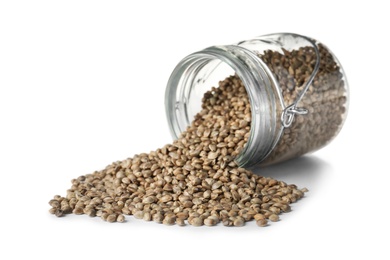 Photo of Overturned jar with hemp seeds on white background