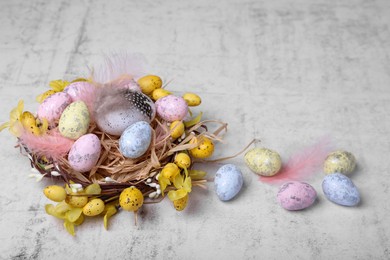 Photo of Decorative nest with many painted Easter eggs on light textured background