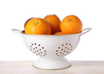 Photo of Fresh oranges in colander on wooden table against white background