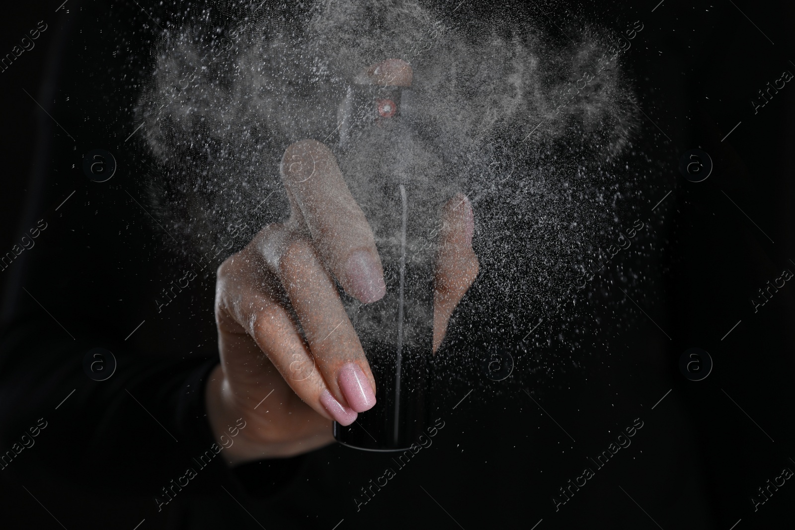 Image of Young woman using pepper spray on black background, closeup