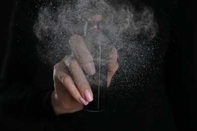 Young woman using pepper spray on black background, closeup