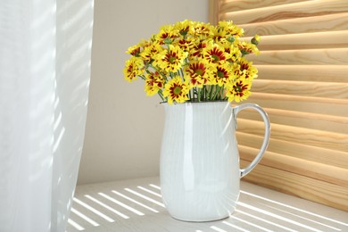 Vase with beautiful chrysanthemum flowers on white windowsill