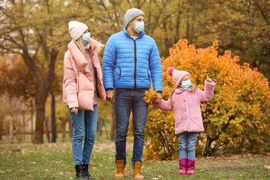 Family in medical masks outdoors on autumn day. Protective measures during coronavirus quarantine