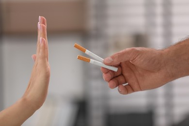Photo of Stop smoking concept. Woman refusing cigarettes on blurred background, closeup