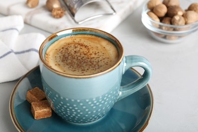 Photo of Coffee with nutmeg powder and brown sugar on light grey table, closeup