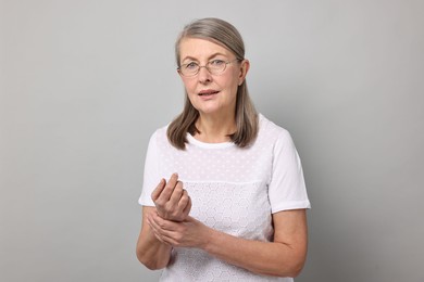 Photo of Arthritis symptoms. Woman suffering from pain in wrist on gray background