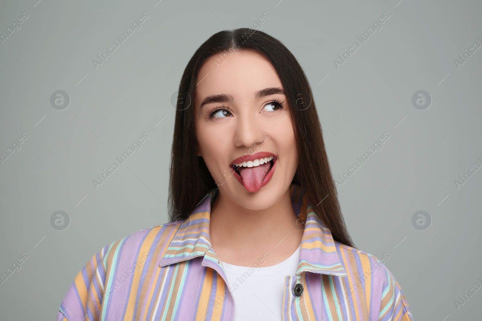 Photo of Happy woman showing her tongue on gray background