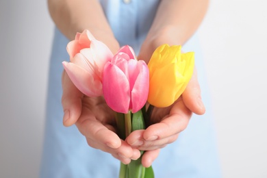 Photo of Girl holding beautiful spring tulips on light background, closeup. International Women's Day