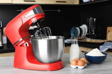 Photo of Modern stand mixer and ingredients on wooden table in kitchen. Home appliance