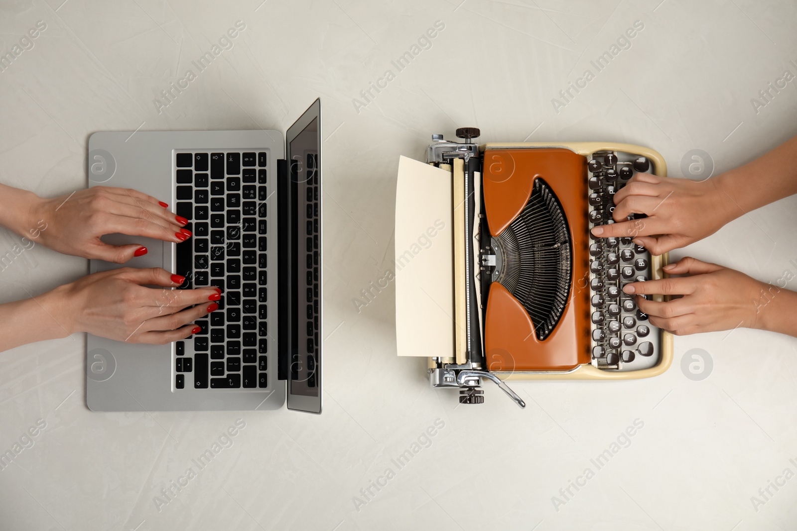 Photo of Women using laptop and old typewriter at light table, top view. Concept of technology progress
