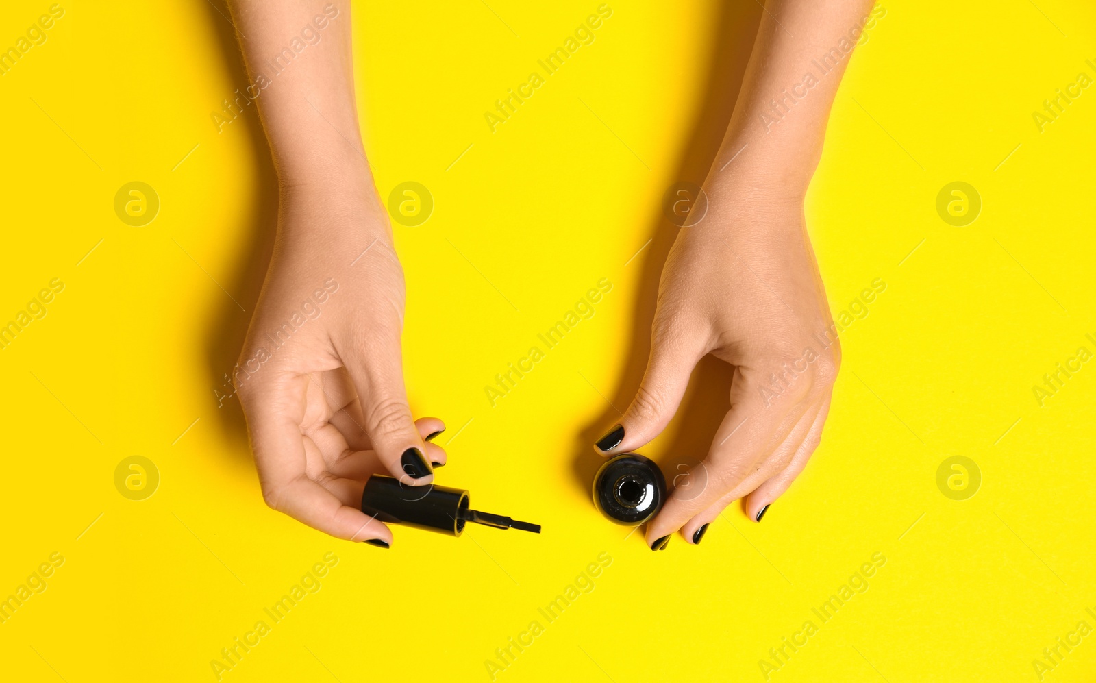Photo of Woman applying nail polish on color background, top view