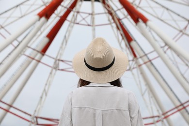 Young woman near Ferris wheel outdoors, back view