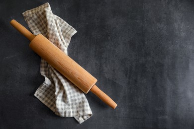 Rolling pin and kitchen towel on black table, top view. Space for text