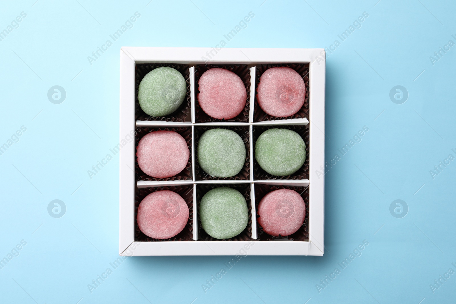 Photo of Many different delicious mochi in box on light blue background, top view. Traditional Japanese dessert