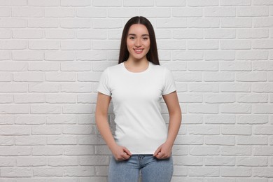 Woman wearing stylish T-shirt near white brick wall