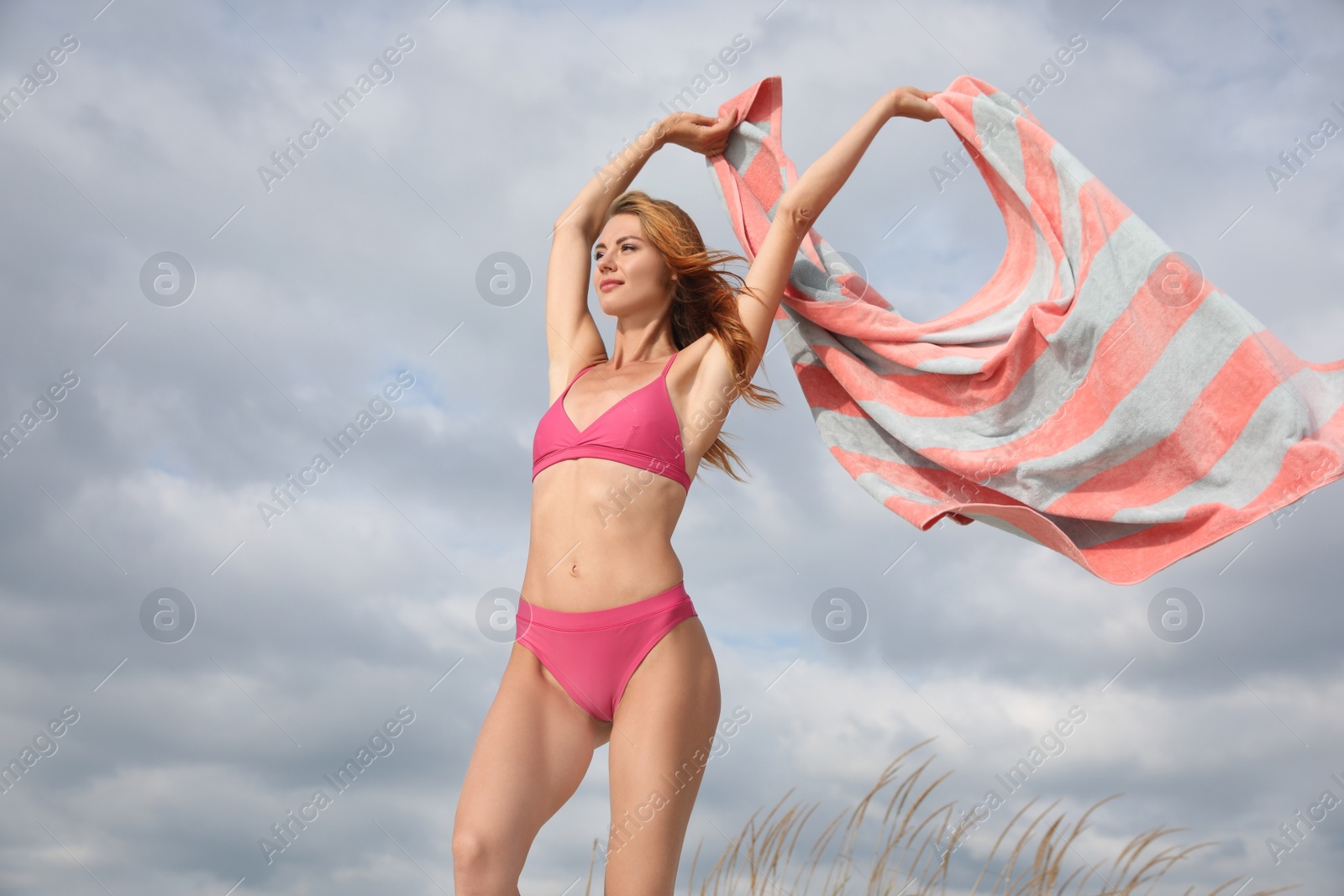 Photo of Beautiful woman in bikini with beach towel against sky