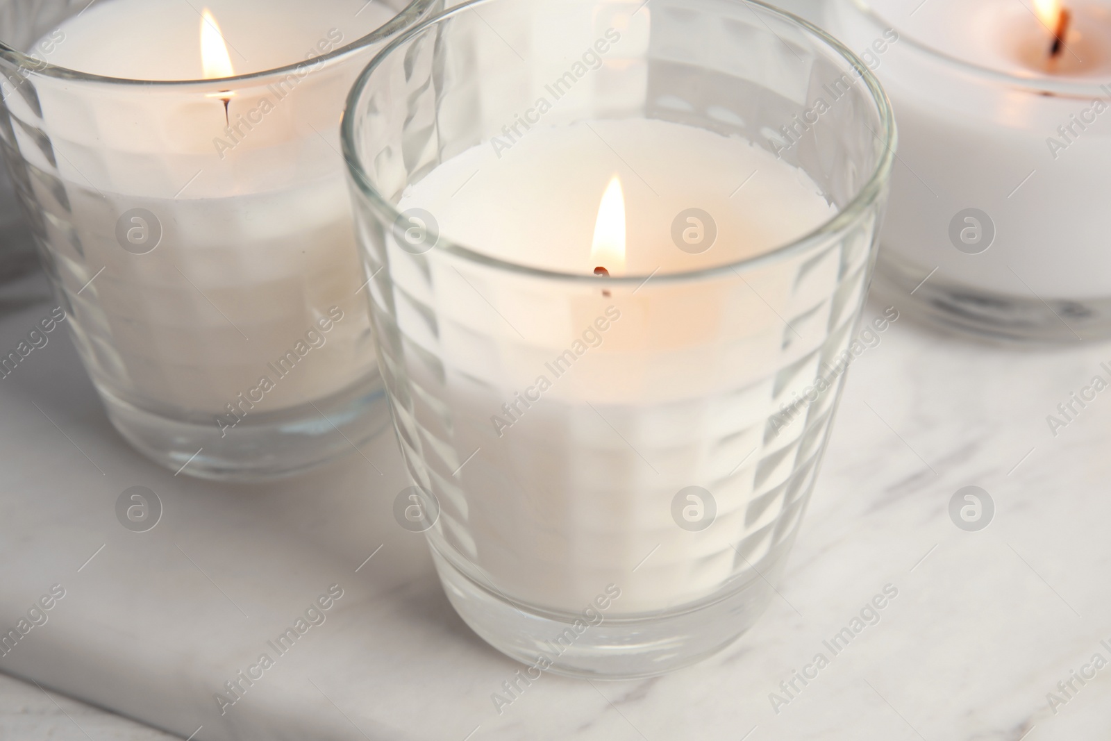 Photo of Burning candles in glass holders on table, closeup