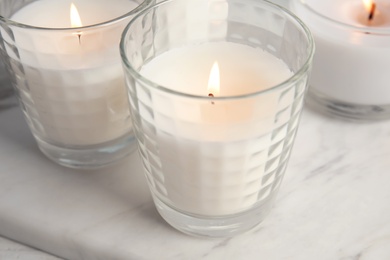 Photo of Burning candles in glass holders on table, closeup