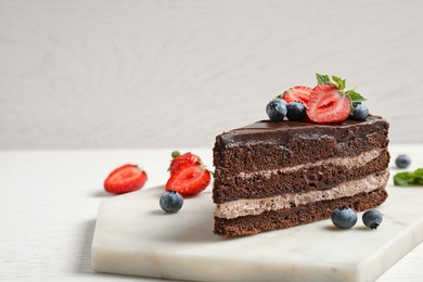 Photo of Delicious fresh chocolate cake with berries on white table