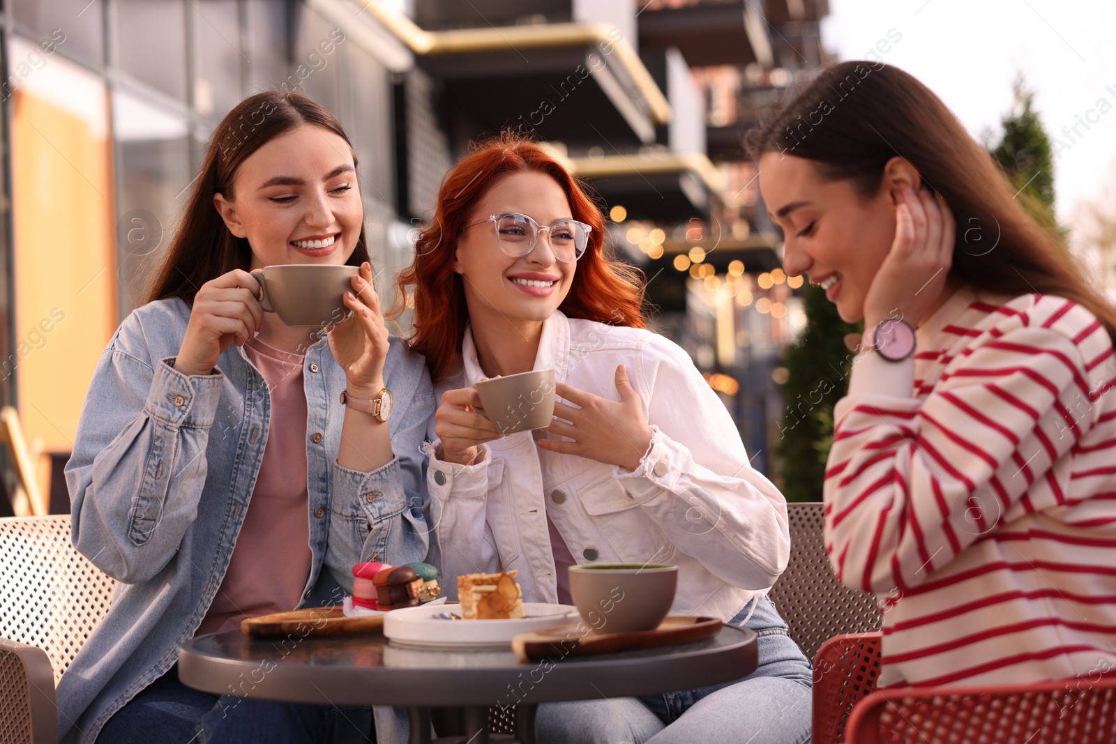 Photo of Happy friends drinking coffee in outdoor cafe