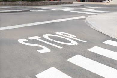 White sign STOP written on asphalt road outdoors