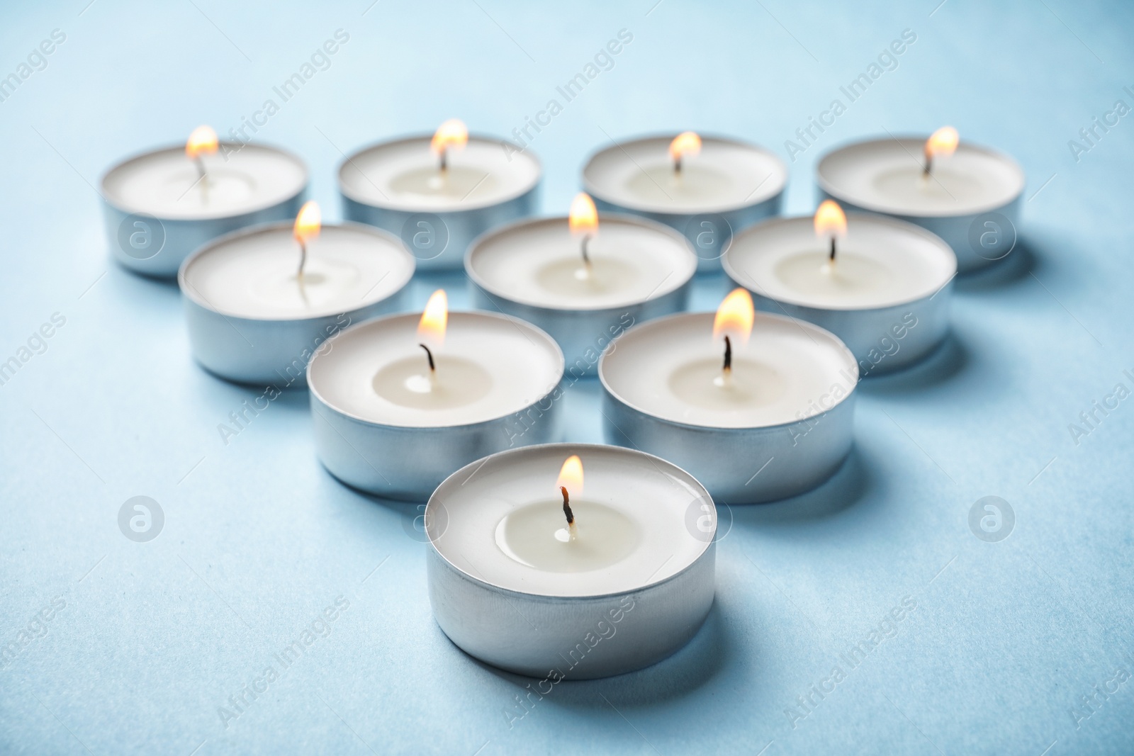 Photo of Small wax candles burning on color background