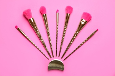 Photo of Set of makeup brushes on pink background, flat lay