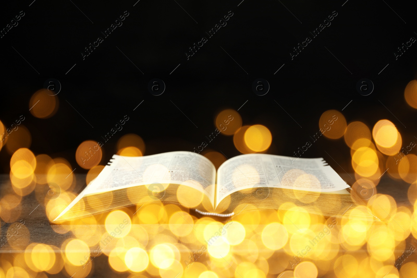 Image of Open Bible on wooden table, bokeh effect