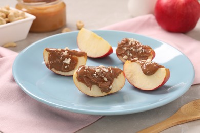 Photo of Slices of fresh apple with nut butter and chopped nuts on table, closeup