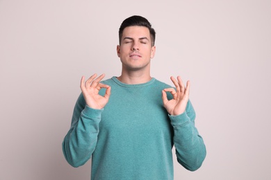 Photo of Man meditating on light background. Stress relief exercise