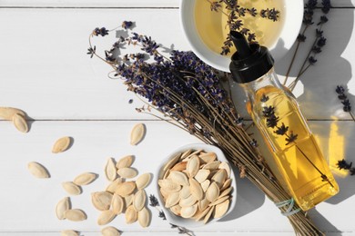 Photo of Healthy cooking oil, lavender flowers and pumpkin seeds on white wooden table, flat lay